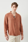 Young man wears a brown Men’s Linen Shirt with white pants by RA Denim