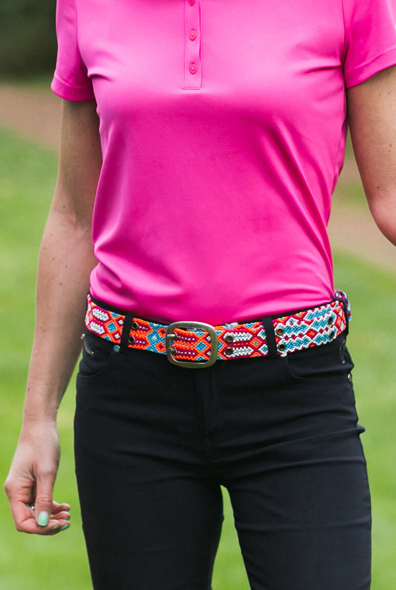 Woman wears ethno-woven-belt-for-women-happy-adriana-smitten with black pants and pink top.